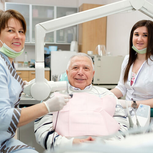 Dentist and nurse taking teeth x-ray radiography to senior man patient in dental office
