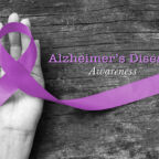 Alzheimer's Disease (AD) Awareness with purple ribbon (clipping path) on human helping hand for World Alzheimers day (month) concept